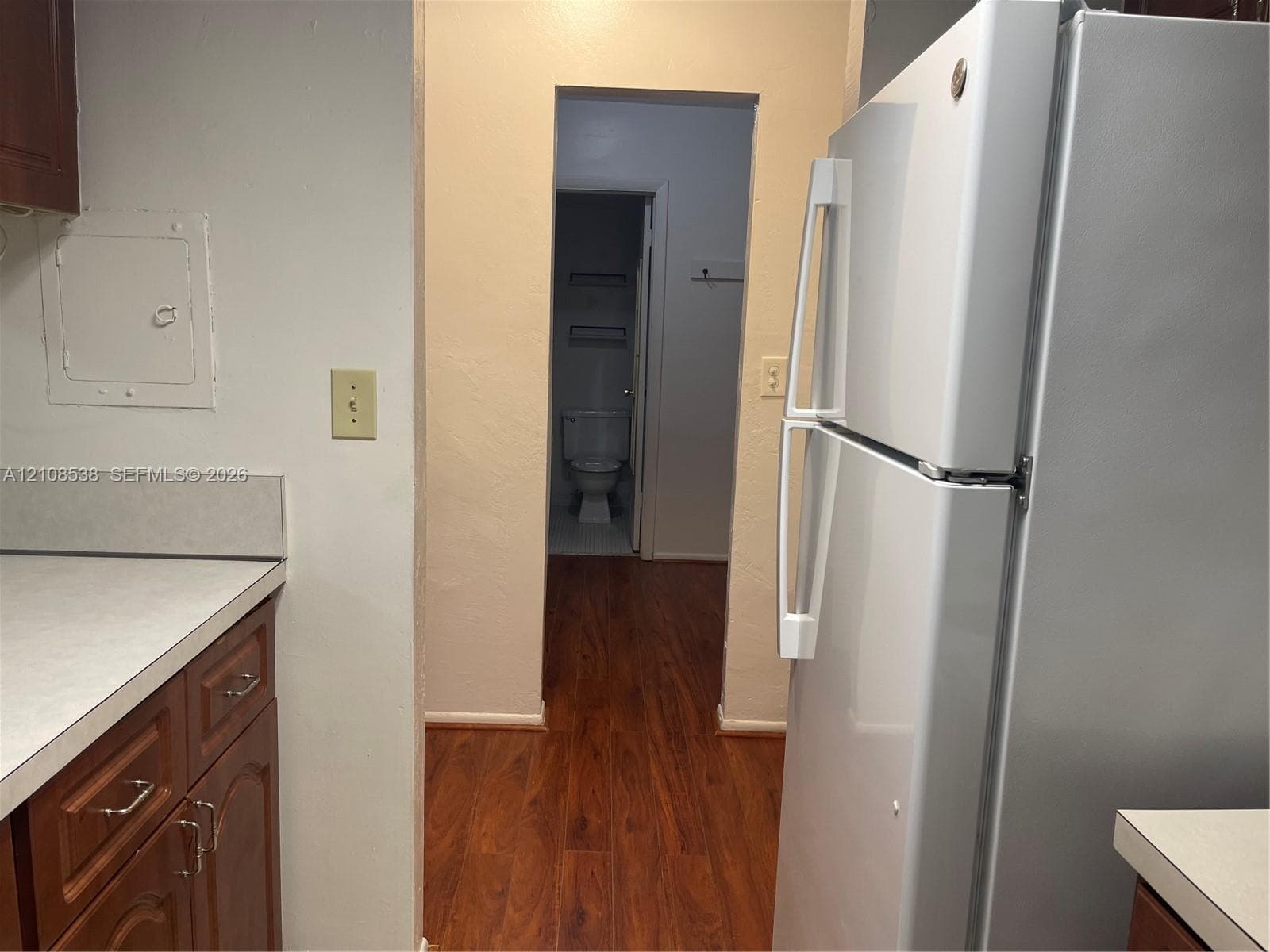 Kitchen featuring stained wood cabinetry, white countertops, a full-size refrigerator, and wood-finish flooring