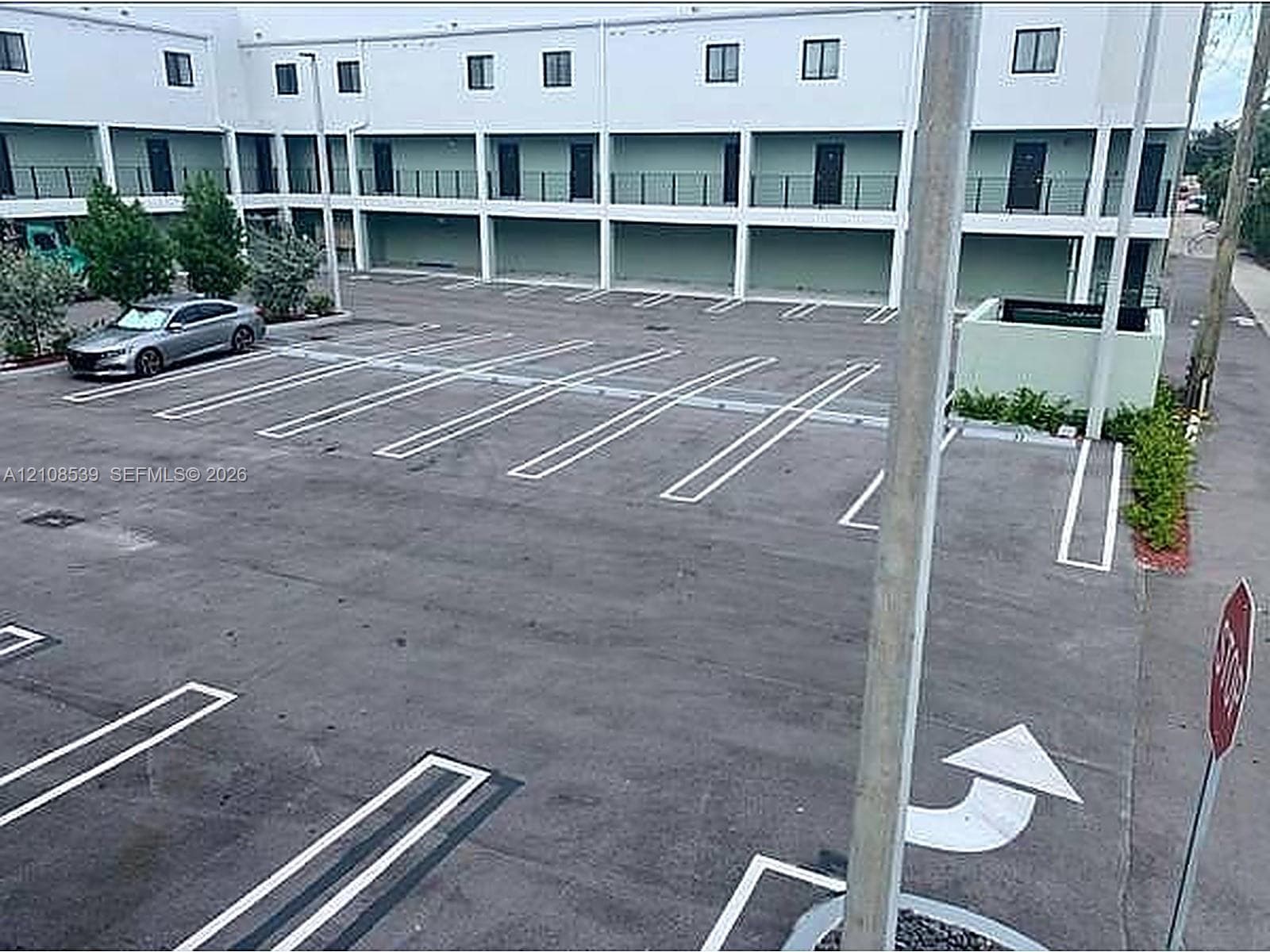 Paved parking lot featuring marked stalls and multi-level structure with metal railings