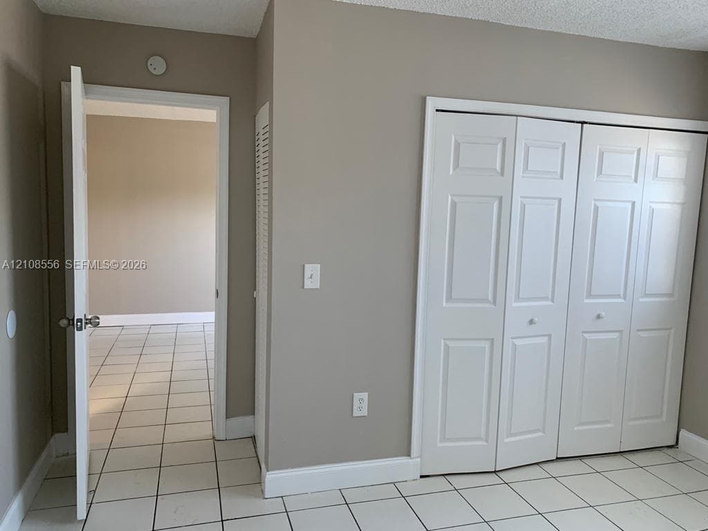 Neutral-tone walls, white ceramic tile flooring, and a multi-panel white closet door