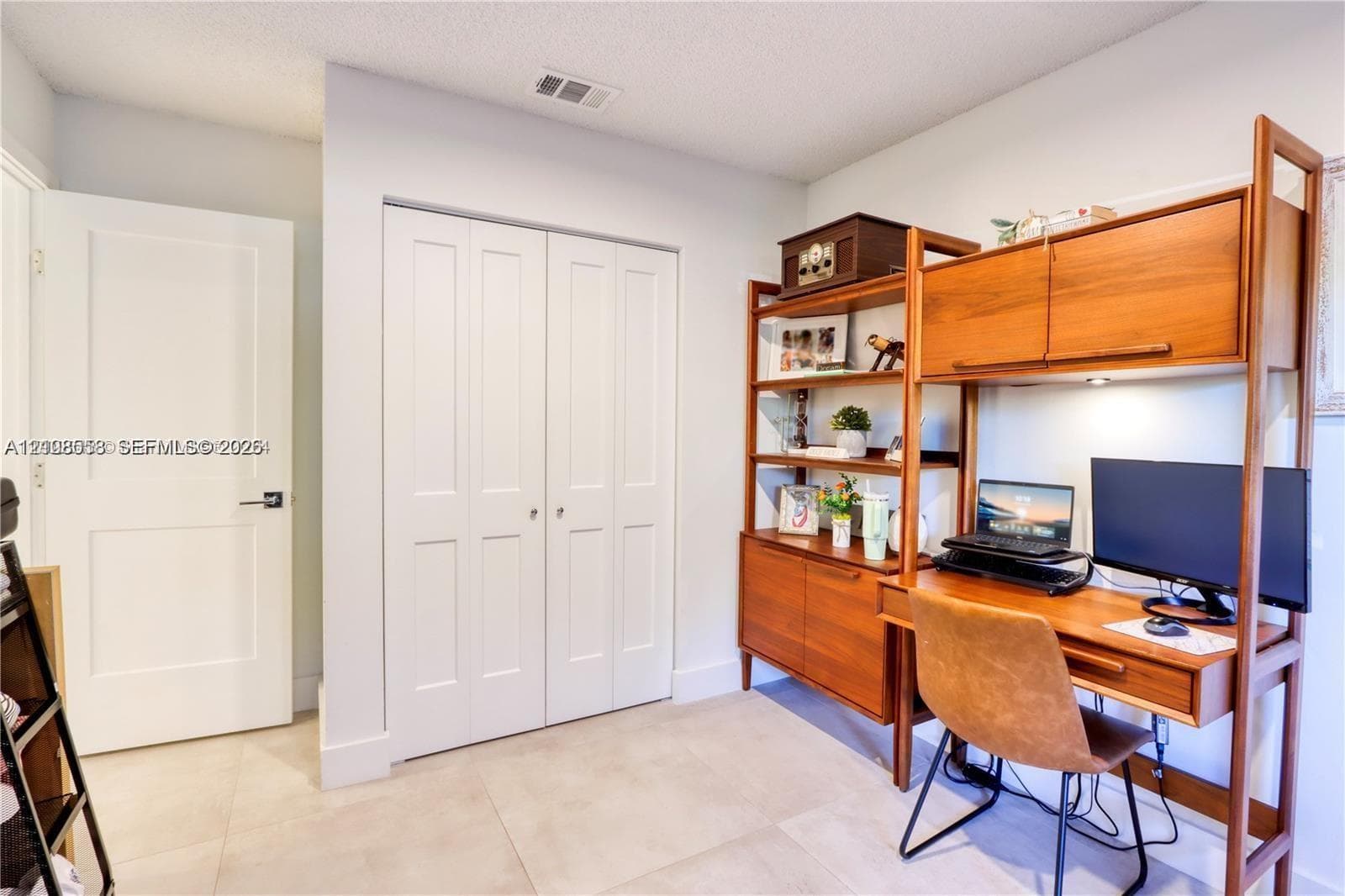 Neutral-toned tile flooring, white interior doors, and double-panel closet doors with hardware