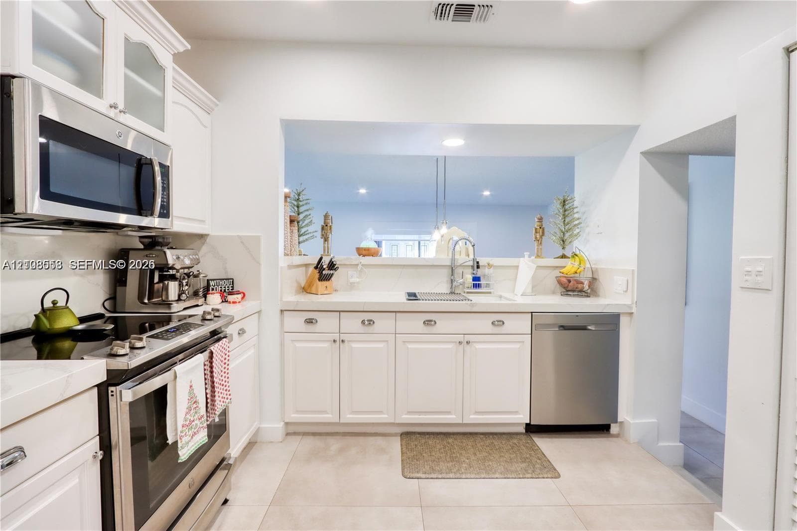 Kitchen featuring white cabinetry, stone-finish countertops, stainless steel appliances, and a recessed pass-through window