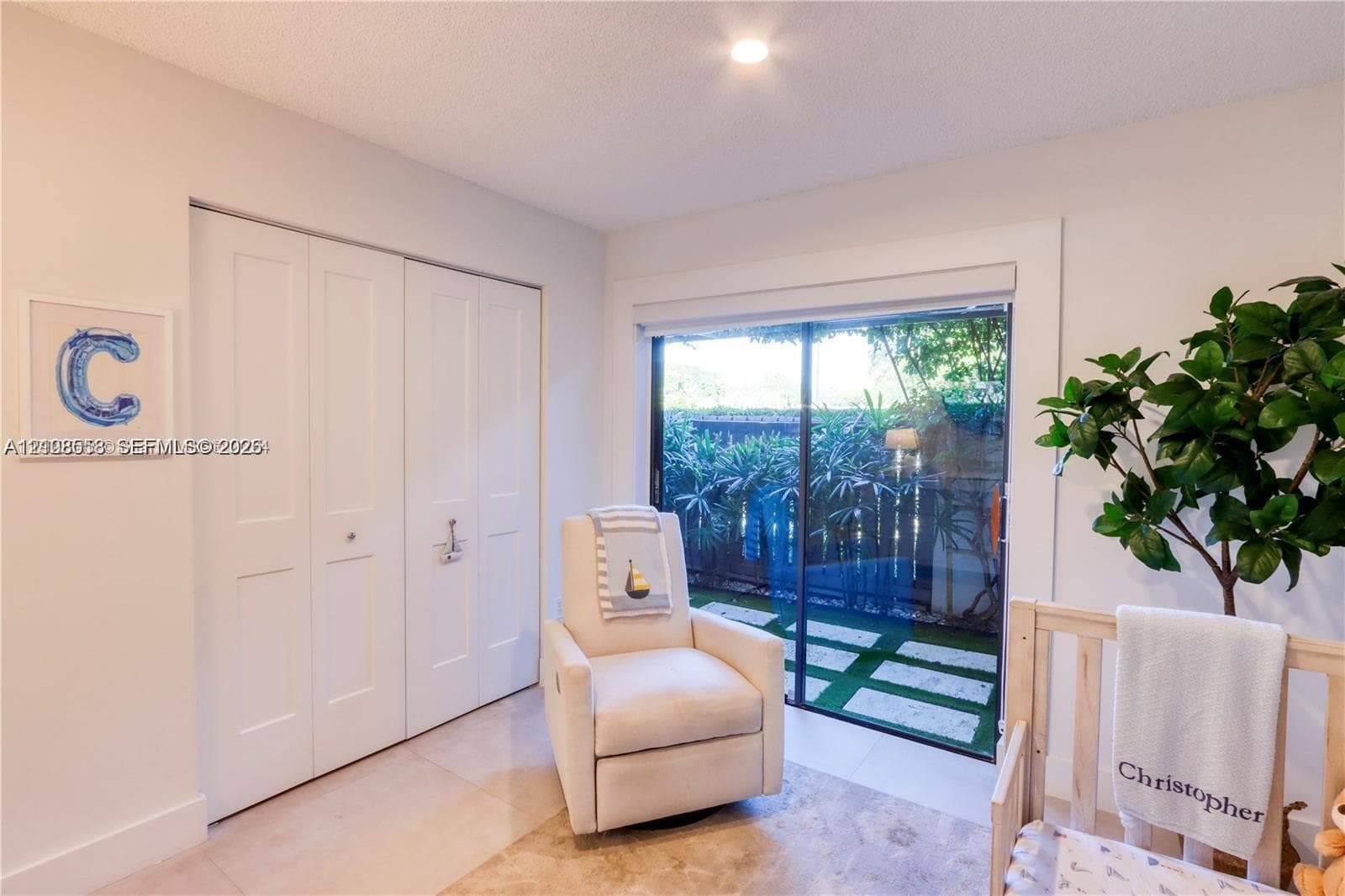 Interior space featuring large format light-toned tile flooring, floor-to-ceiling bifold closet doors, and a sliding glass door providing external access
