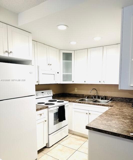 Kitchen featuring white cabinetry with glass-panel accents, stone-patterned laminate countertops, double-basin stainless steel sink, recessed lighting, and tile flooring