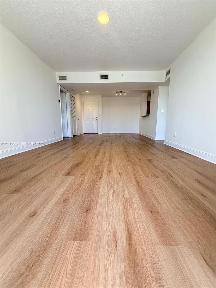 Open-concept interior featuring light wood-finish flooring, neutral walls, and flush-mount ceiling lighting