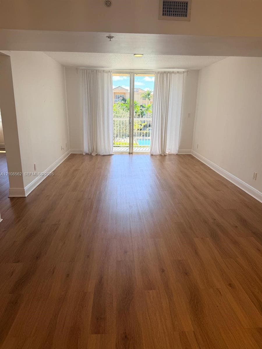 Living area featuring wood-finish flooring and glass sliding doors opening to a private balcony