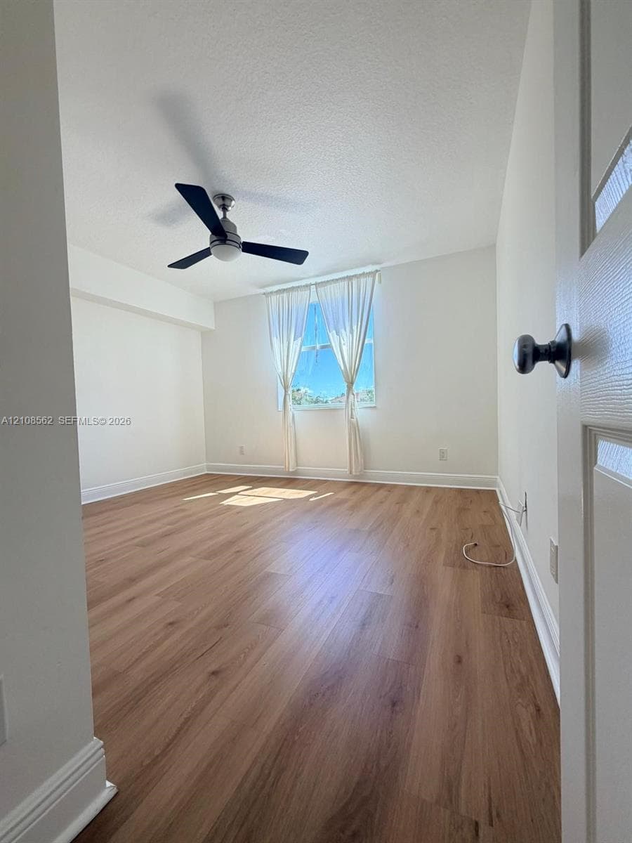 Interior space featuring wood-finish flooring, neutral wall paint, and a modern ceiling fan