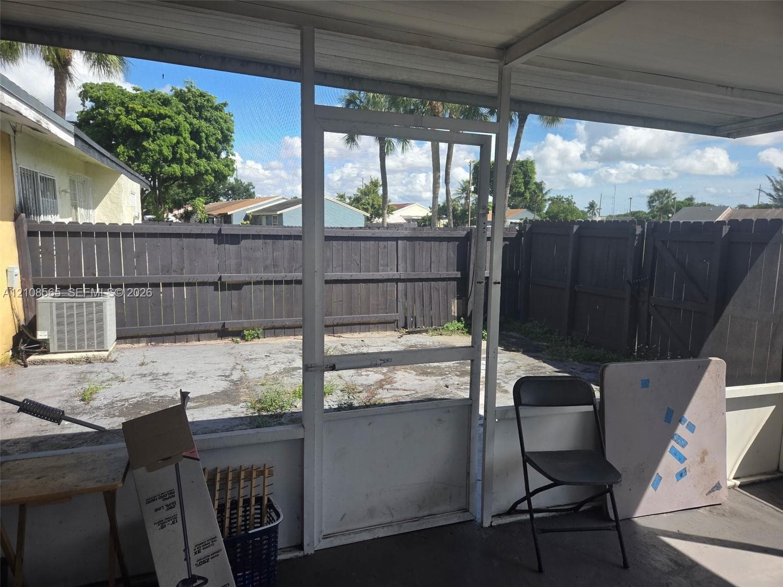 Screened-in porch featuring a concrete patio, wood-style privacy fencing, and an external HVAC unit