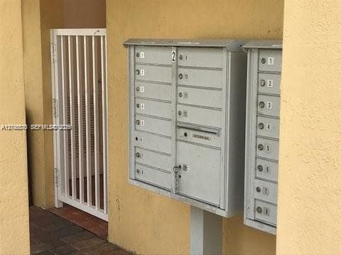 Wall-mounted metal mail distribution center featuring individual locking compartments and a white vertical bar gate