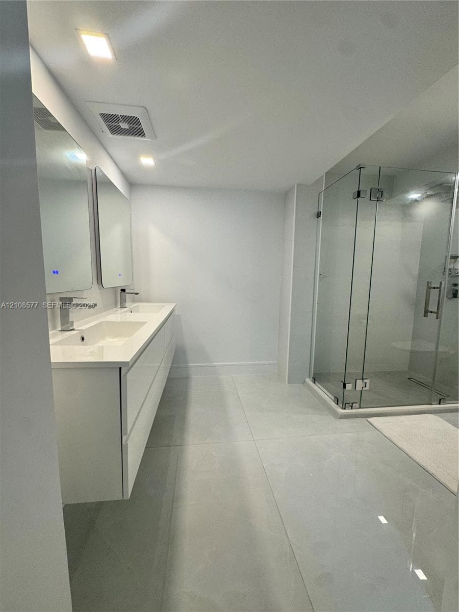Floating dual-sink vanity with a solid-surface countertop, glass-enclosed shower, polished large-format floor tile, and rectangular wall-mounted mirrors