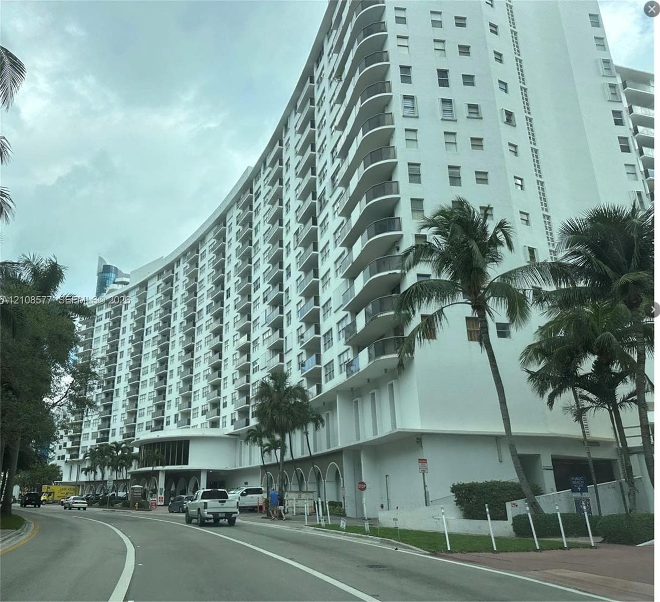 High-rise residential exterior featuring a curved facade, private balconies, and an arched ground-level entryway