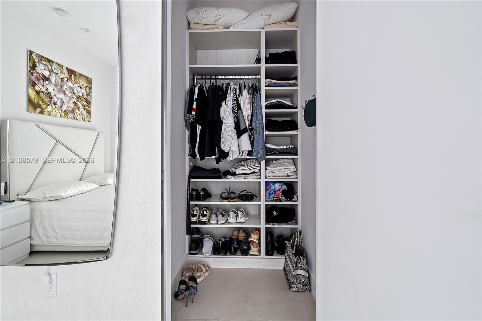 Built-in closet featuring multi-level shelving, integrated hanging rods, and a white finish