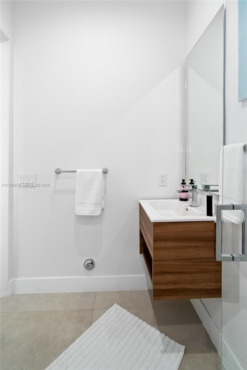 Wall-mounted wood-finish floating vanity with an integrated rectangular sink, chrome single-handle faucet, and large-format tile flooring