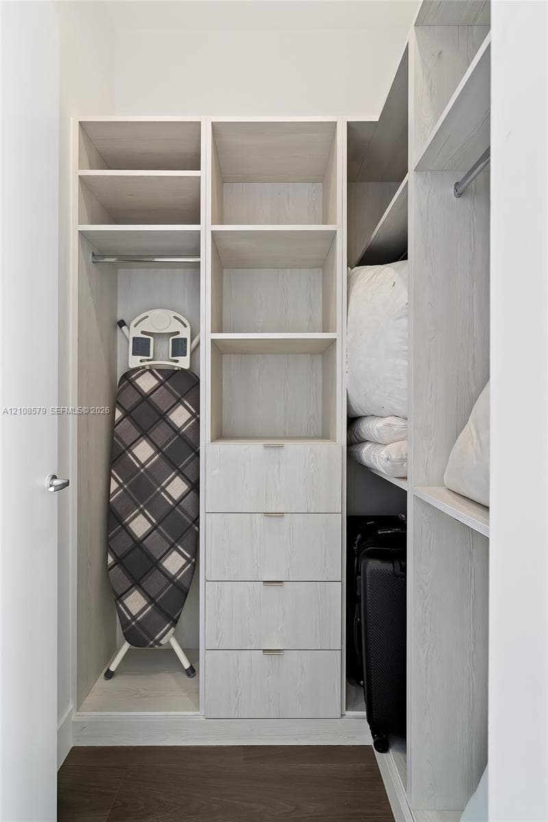 Custom built-in closet featuring light wood-finish shelving, integrated drawers with metal pulls, and multiple clothing rods