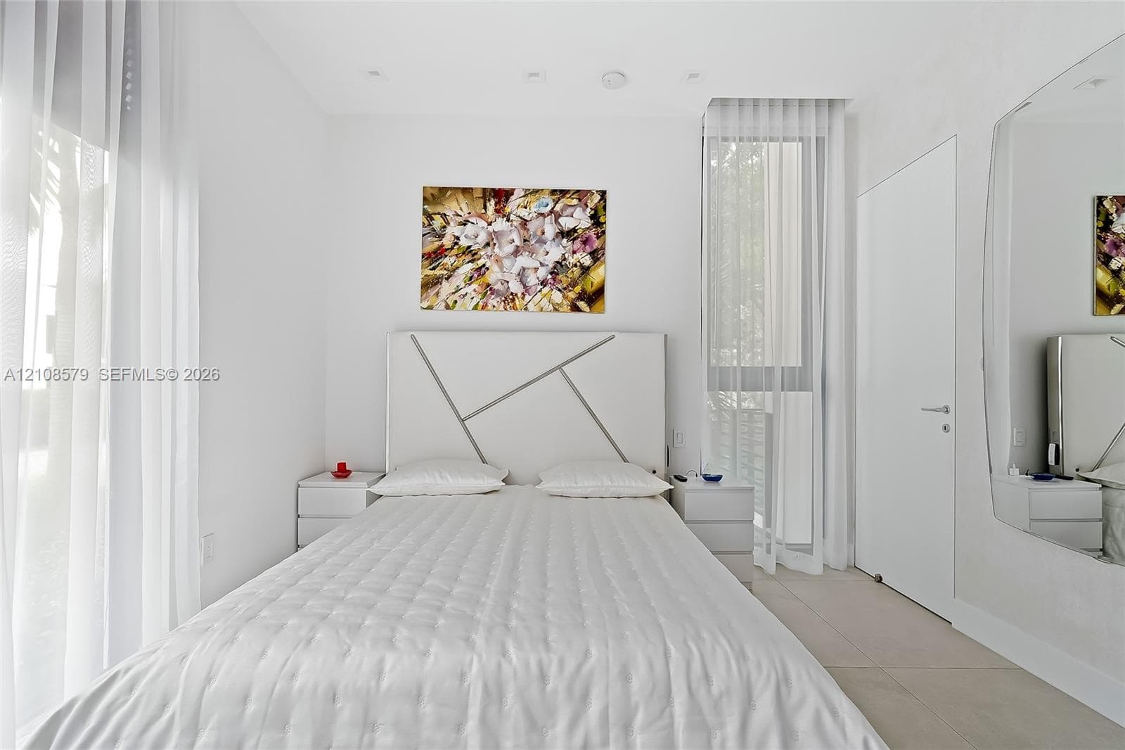 Floor-to-ceiling windows with sheer drapery, recessed ceiling lighting, large-format tile flooring, and a full-height wall-mounted mirror