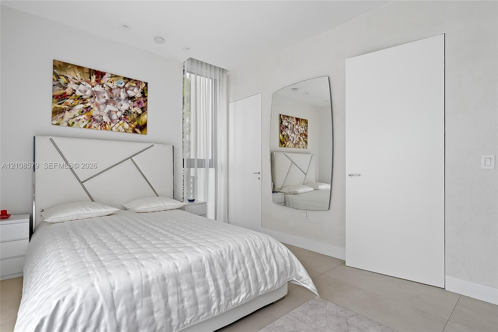 Neutral-toned interior featuring floor-to-ceiling windows with vertical blinds, large-format tile flooring, and solid-core interior doors with satin-finish hardware