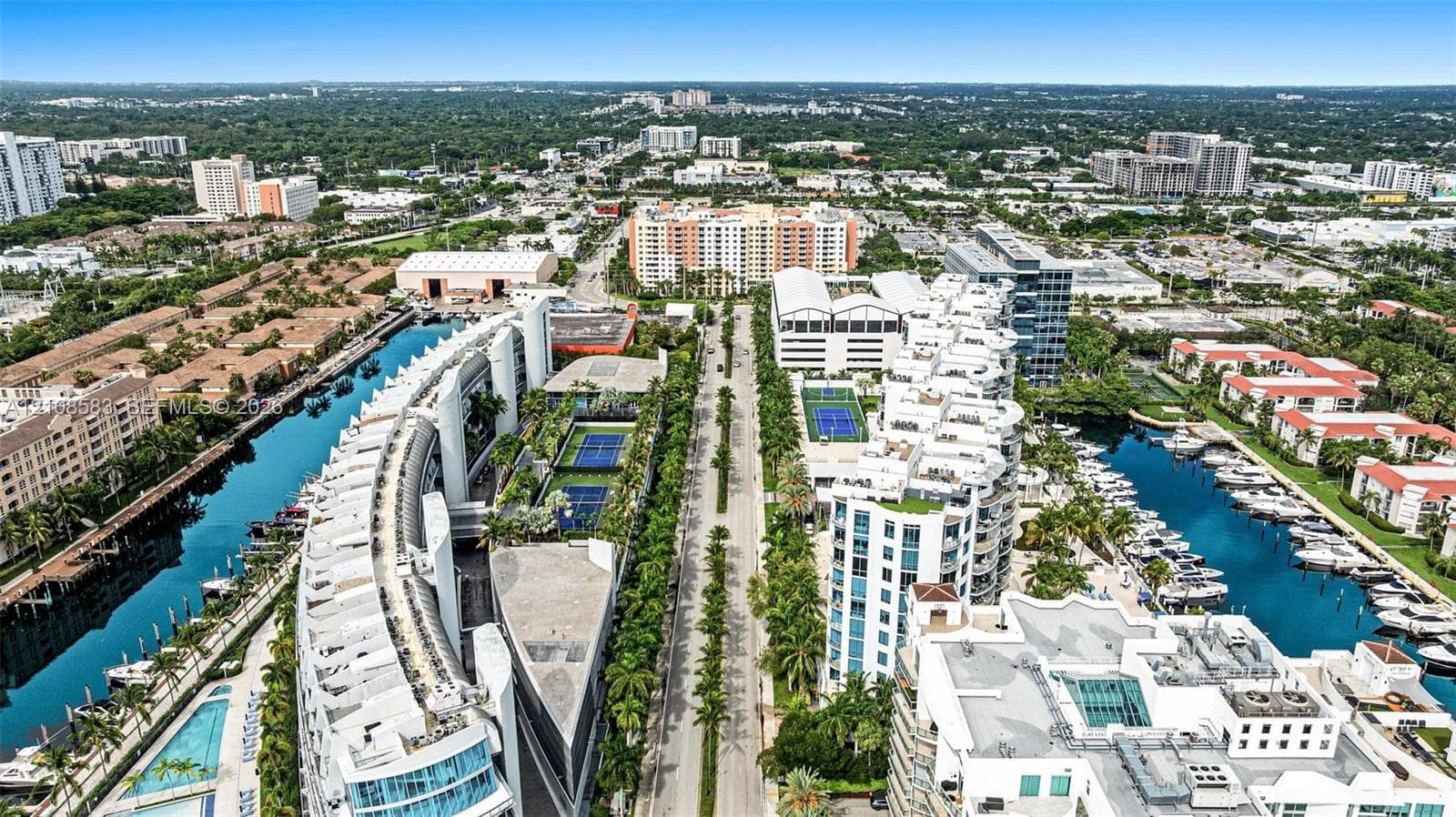 Aerial perspective of a multi-building residential complex featuring deep-water boat slips, on-site tennis courts, and swimming pools