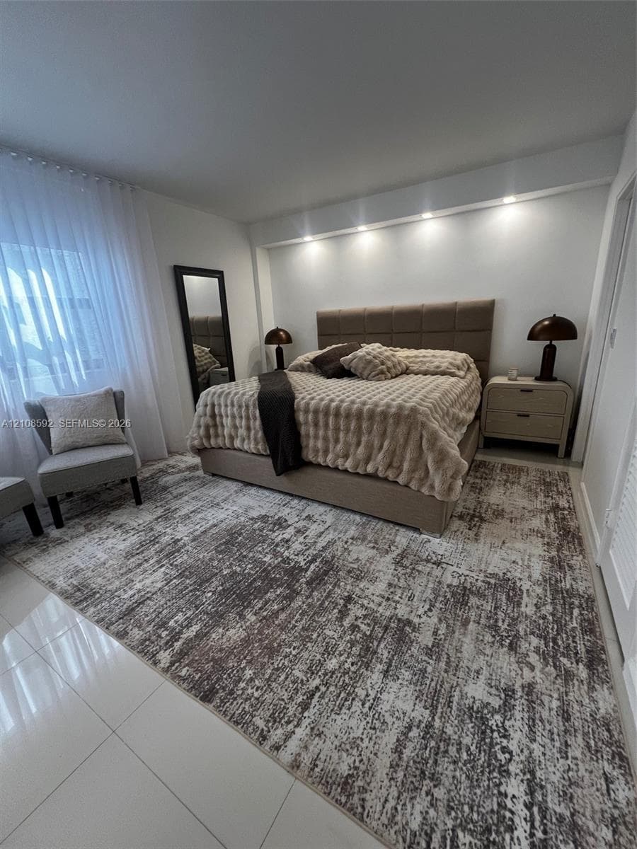 Bedroom featuring white tile flooring, neutral wall-to-wall carpeting, recessed architectural ceiling lighting, and floor-to-ceiling sheer window treatments