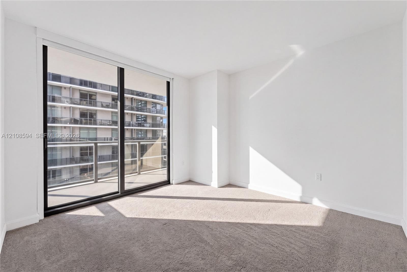 Full-height sliding glass door, neutral carpeting, and private balcony access