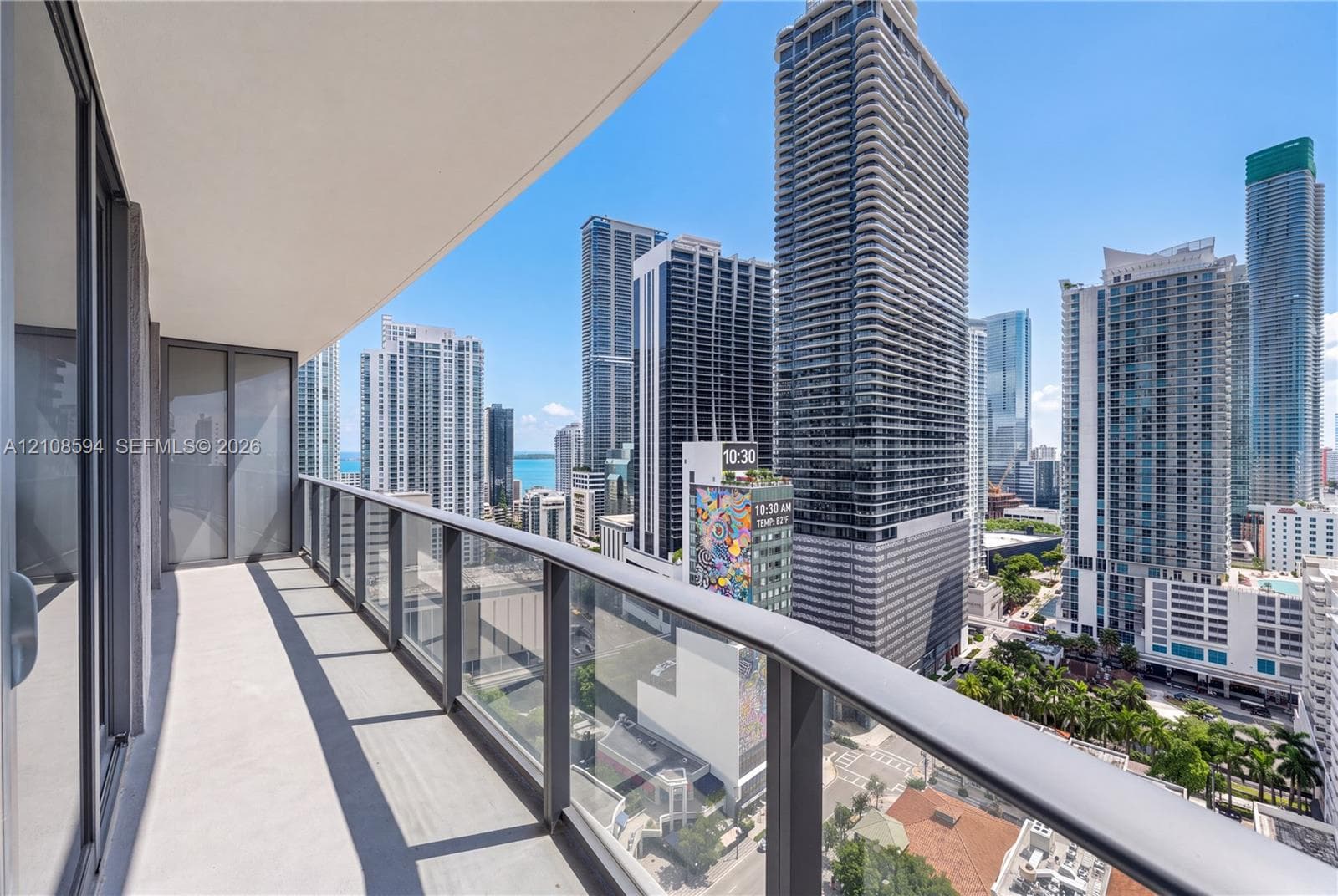 Covered balcony featuring concrete flooring and a glass-paneled railing