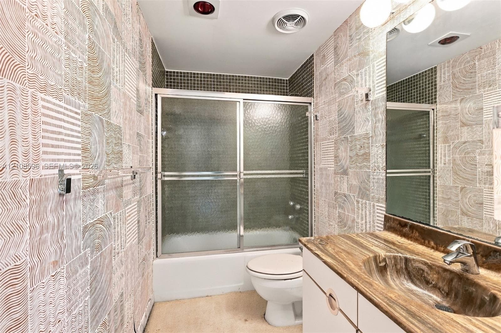 Textured tile wall surfaces, custom integrated basin vanity with countertop, and sliding glass shower enclosure