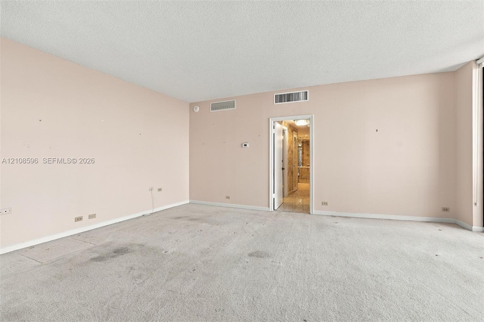 Expansive interior room featuring neutral wall finishes, plush carpeting, and recessed ceiling HVAC registers
