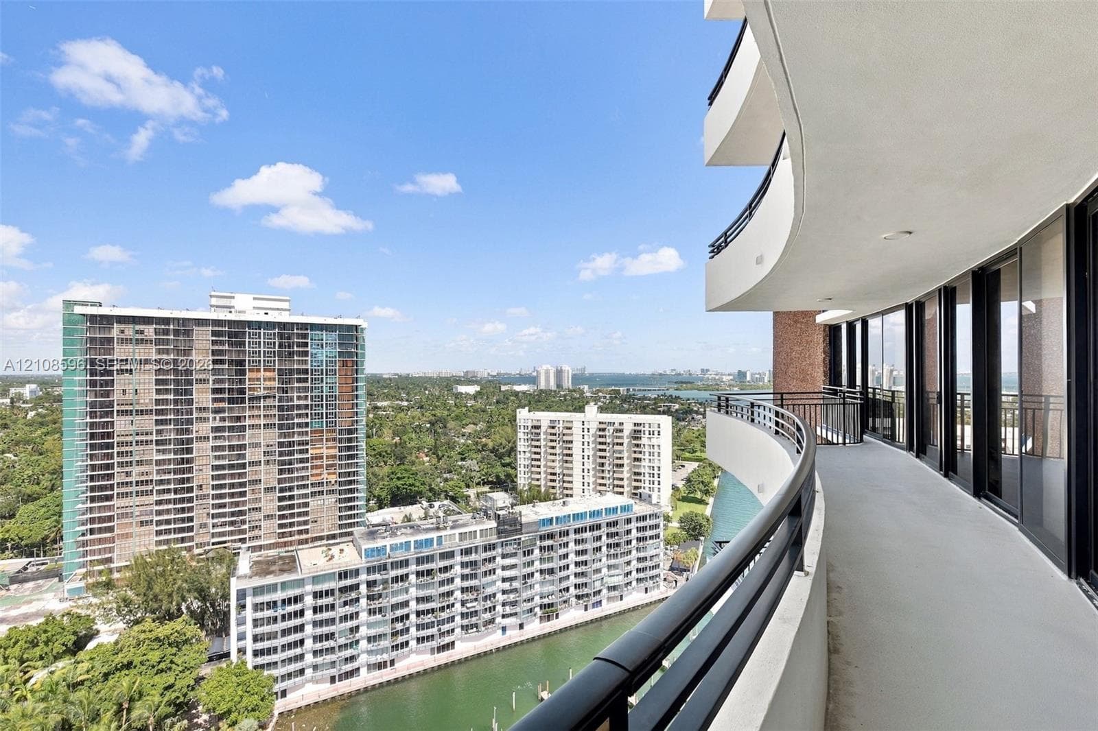 Curved exterior balcony with metal railings and floor-to-ceiling glass sliding doors