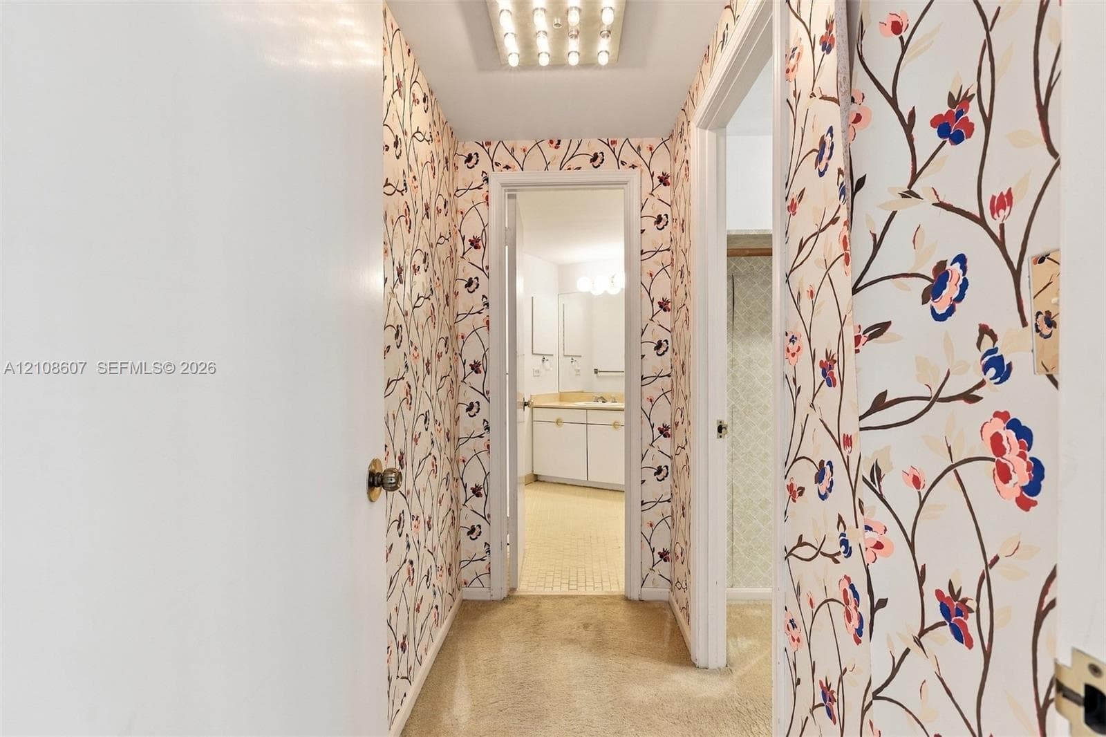 Hallway featuring floral-patterned wallpaper, flush-mount lighting, and solid-core interior doors with metallic hardware