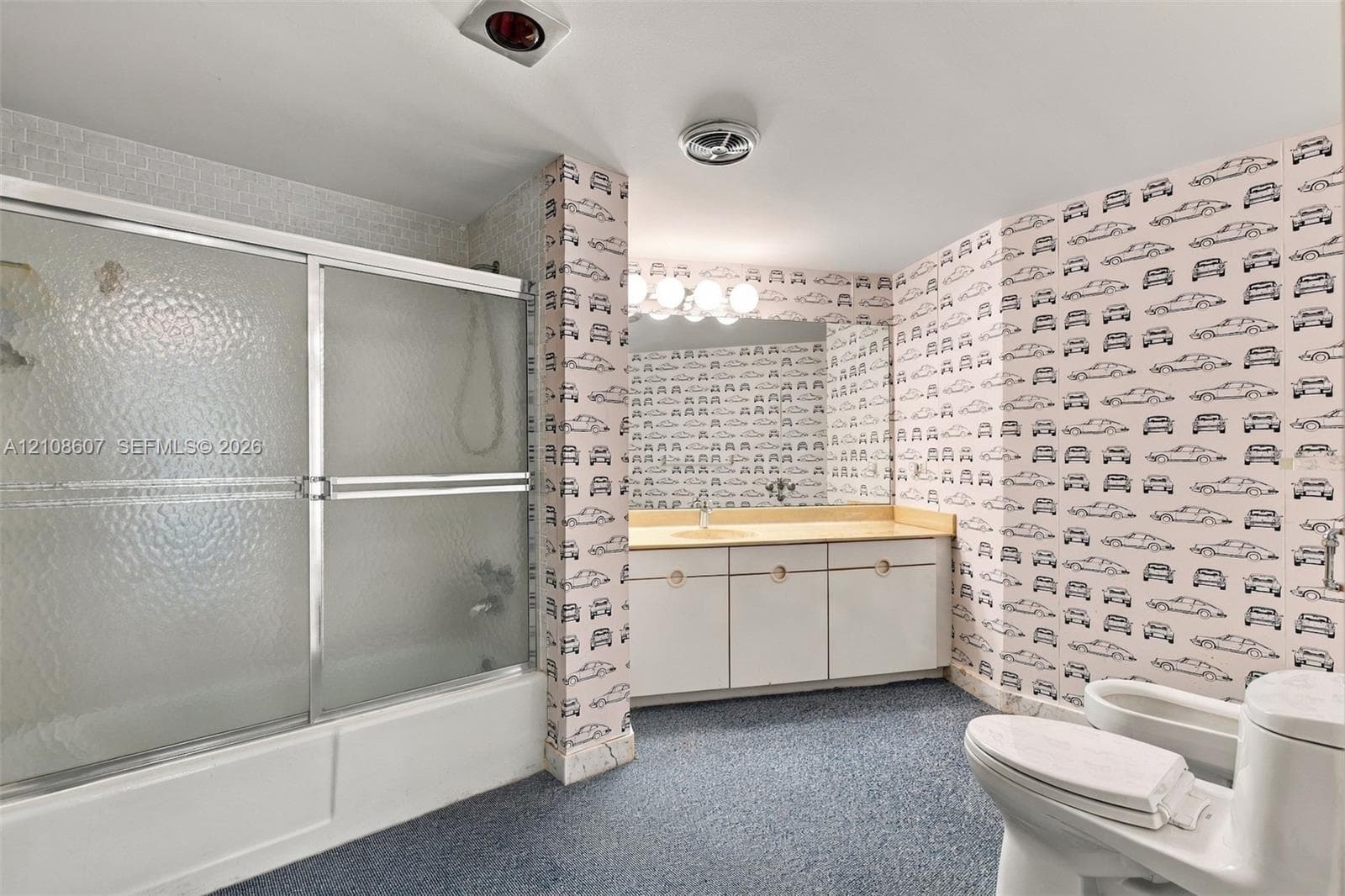 Bathroom featuring a sliding glass shower door, built-in vanity with countertop, large wall-mounted mirror, and multi-bulb light fixture