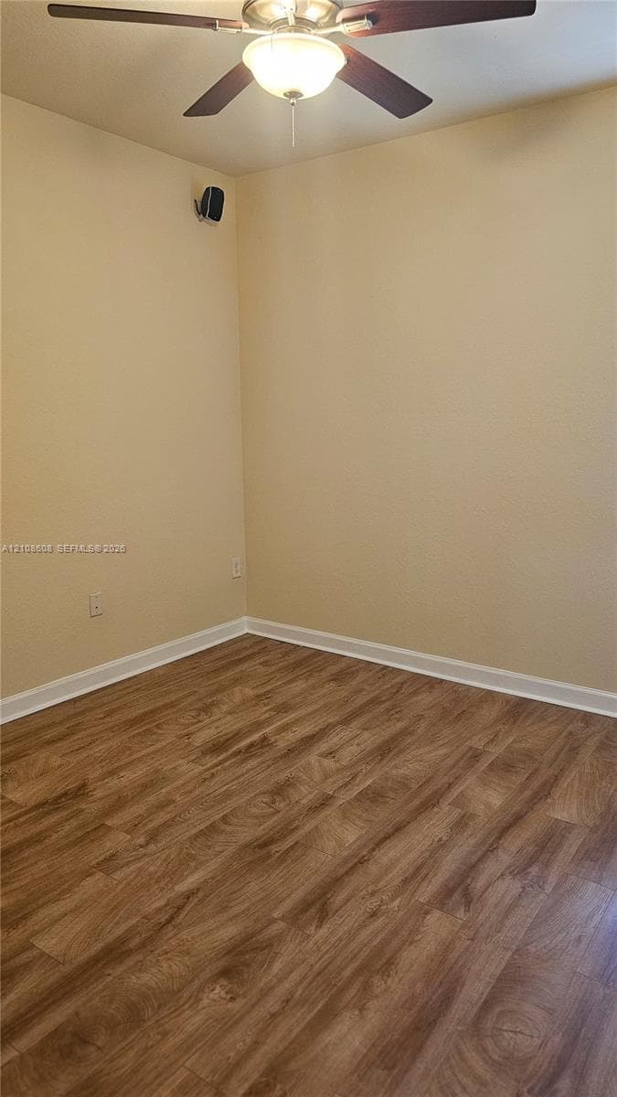 Room featuring wood-finish flooring and a ceiling fan with integrated lighting