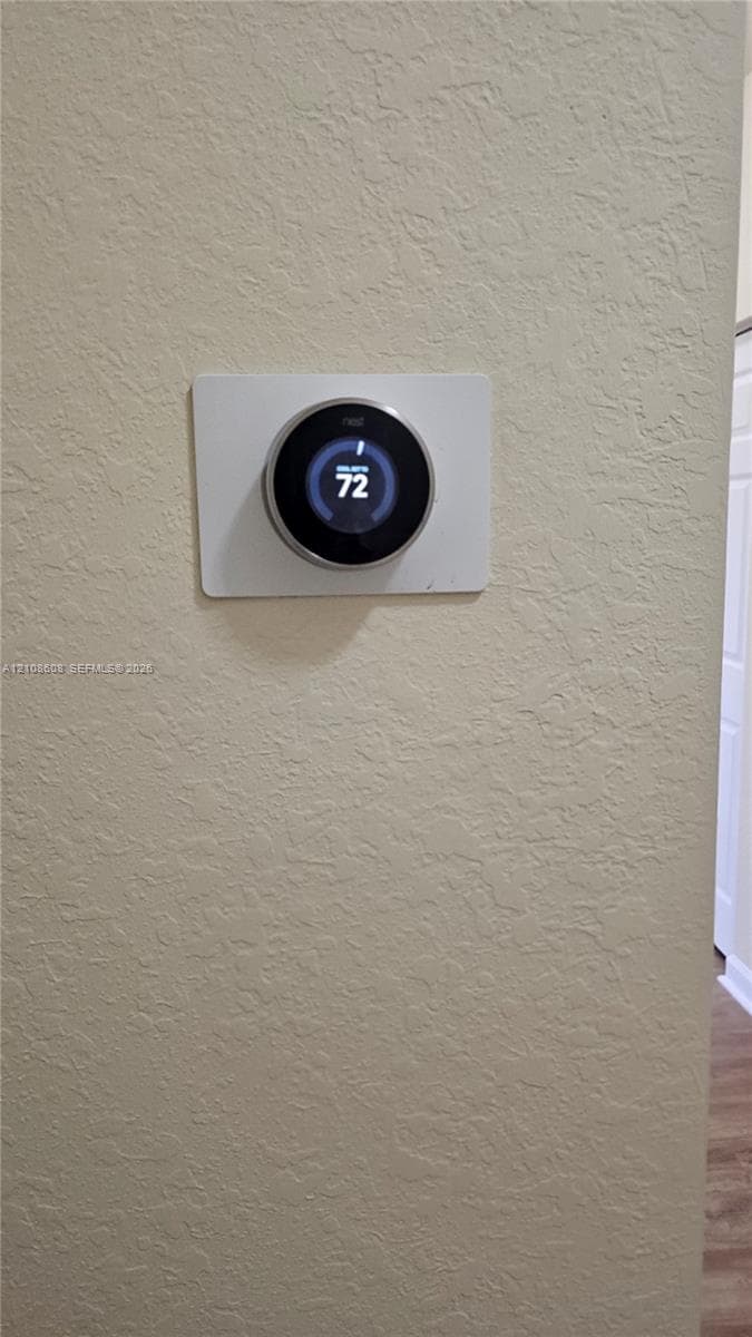 Smart home-integrated circular digital thermostat mounted on a textured wall