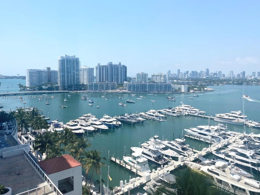Elevated outdoor terrace featuring a terracotta-tiled roofline, metal railing, and panoramic water, marina, and city skyline scenery