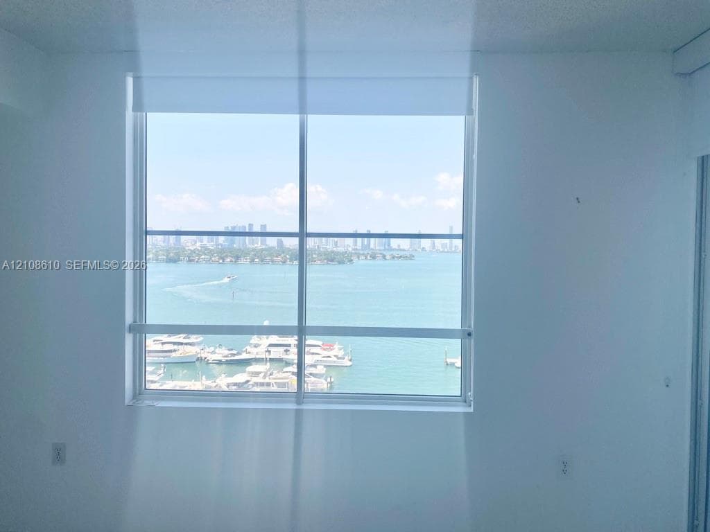 Large picture window with metal frame featuring an expanse of water, marina, and city skyline