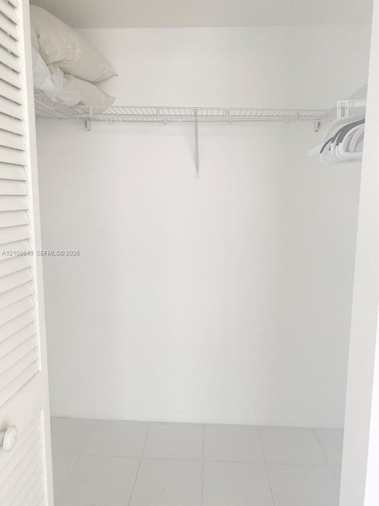 Closet featuring white louvered doors, wire shelving, and tile flooring