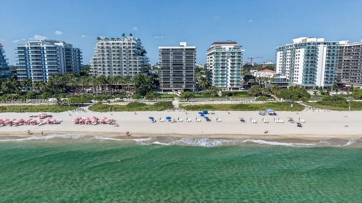 Aerial perspective of coastal high-rise properties featuring direct beach access, extensive sandy shoreline, and proximity to ocean waters