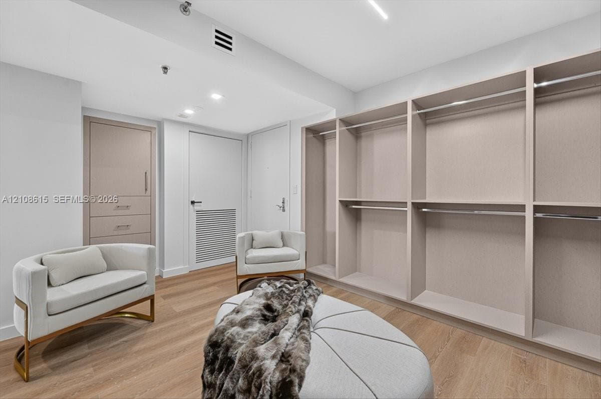 Custom built-in storage system featuring light wood-finish shelving and hanging rods, integrated drawer unit with brushed metal hardware, and wood-finish flooring