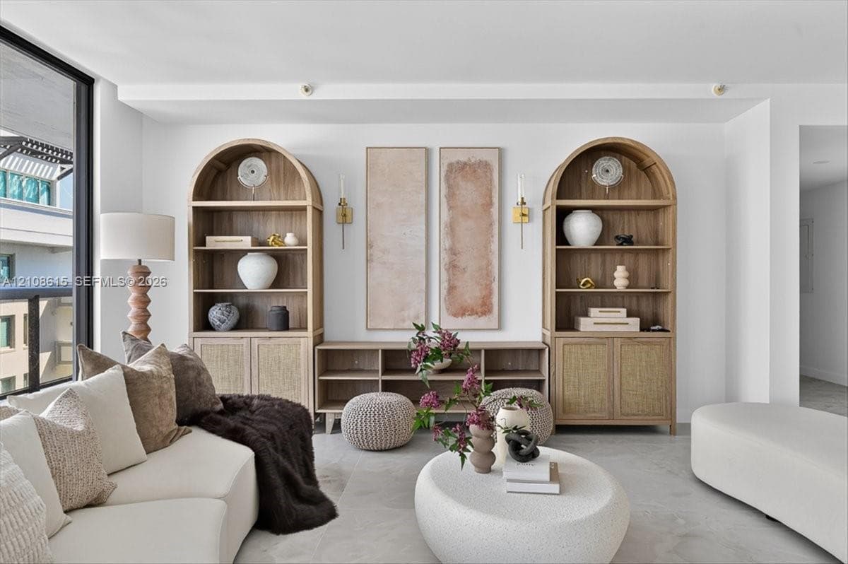 Custom built-in wood shelving units with arched tops, integrated lower cabinet storage, floor-to-ceiling glass window panel, and wall-mounted metallic sconces