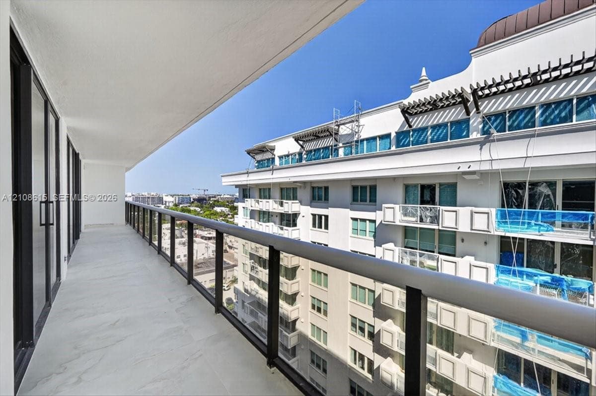 Covered balcony featuring tile flooring, glass panel railings, and dark metal framing