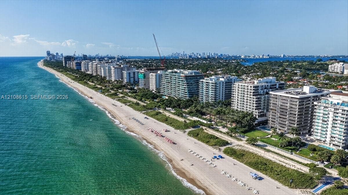 Coastal aerial perspective featuring direct oceanfront positioning, expansive sandy beach frontage, and mature landscaping