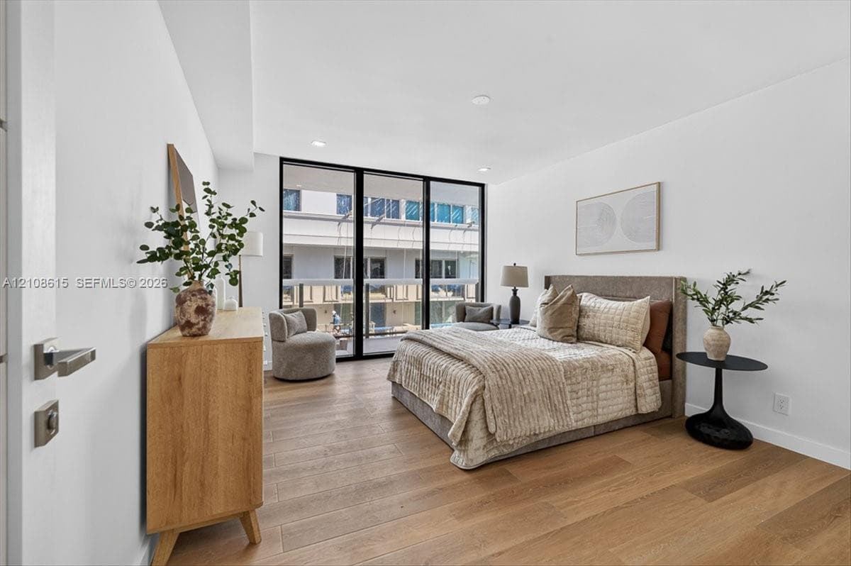 Wood-finish flooring, floor-to-ceiling glass panel door, recessed lighting, and modern hardware fixtures