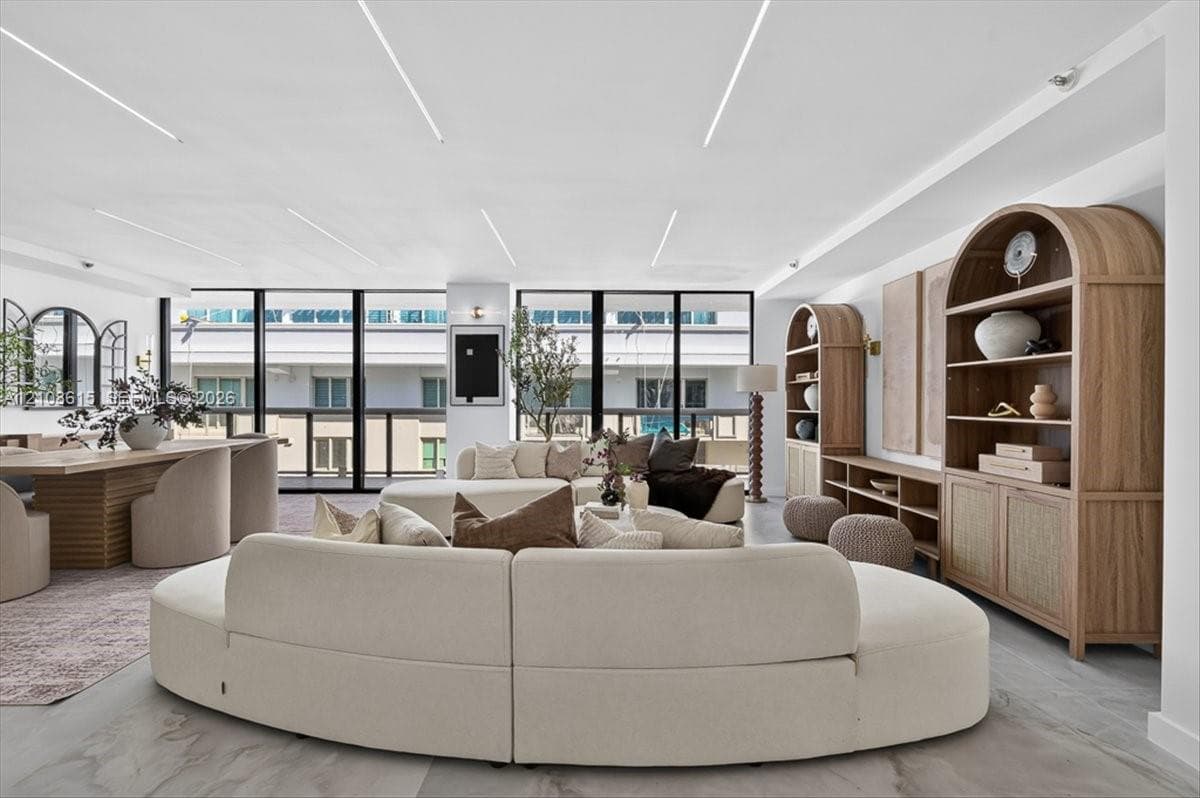 Floor-to-ceiling windows, recessed linear ceiling lighting, built-in arched wood cabinetry, and large-format tile flooring