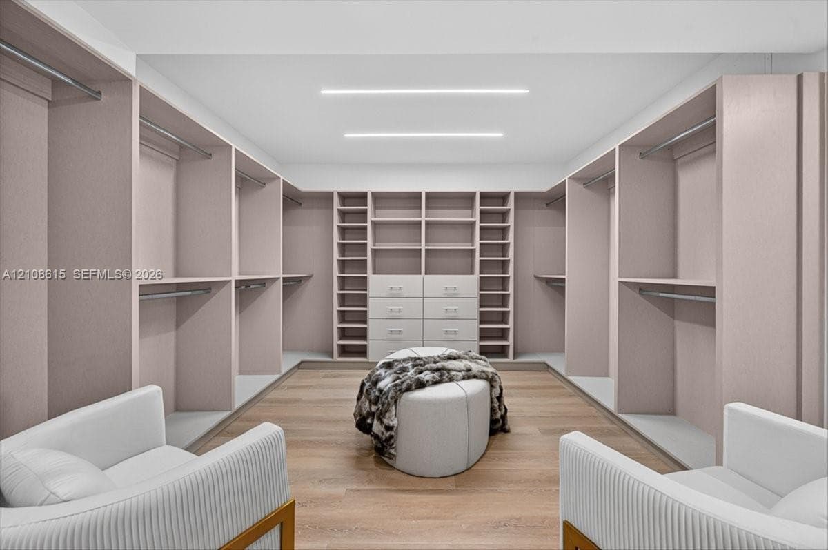 Custom walk-in closet featuring floor-to-ceiling built-in cabinetry, integrated drawer storage, wood-finish flooring, and recessed linear ceiling lighting