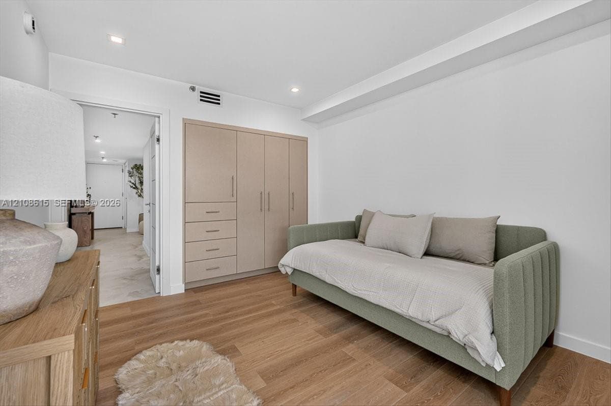 Neutral-toned, built-in cabinetry featuring integrated storage drawers and recessed ceiling lighting over wood-finish flooring