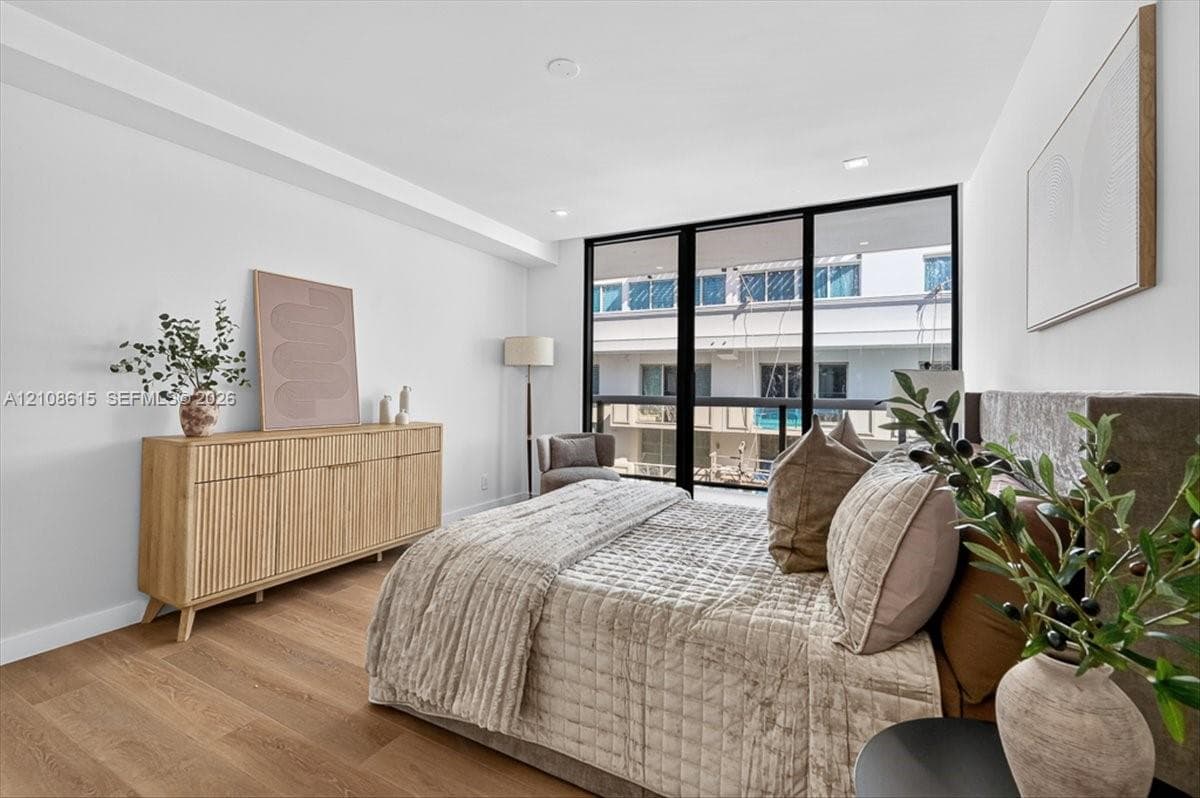 Floor-to-ceiling windows with black frames, wood-finish flooring, and recessed ceiling lighting