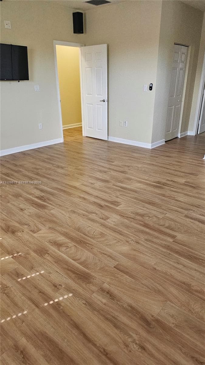 Interior space featuring wood-finish flooring, neutral wall tones, multi-panel interior doors, and a wall-mounted speaker