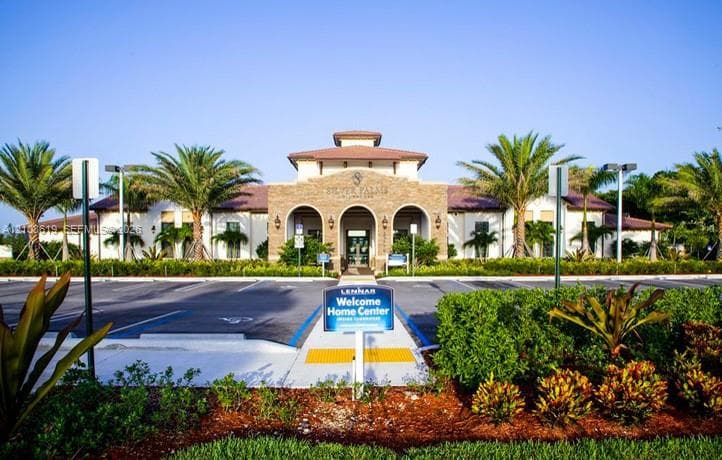 Stucco exterior featuring a stone-veneer arched entryway, tile roof, and manicured landscaping with palm trees