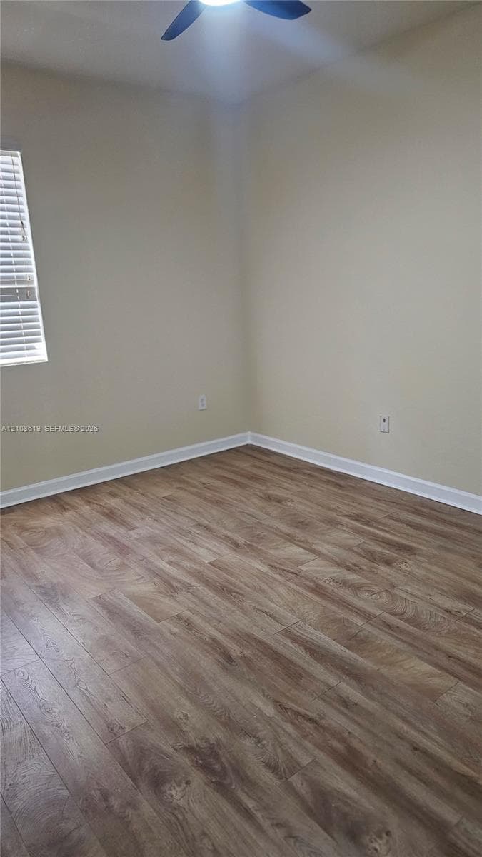 Neutral wall tones, wood-finish flooring, and a ceiling-mounted fan with integrated lighting