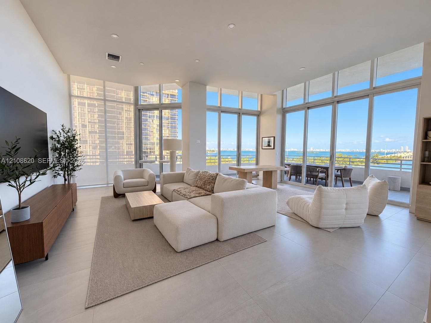 Floor-to-ceiling glass windows, expansive water backdrop, recessed lighting, and large-format tile flooring