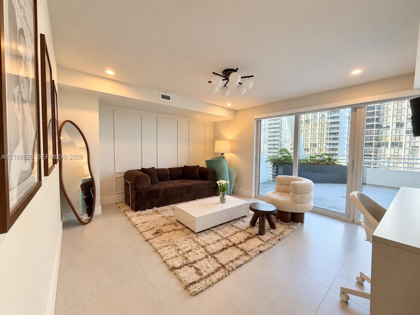 Living area featuring large-format tile flooring, decorative wall molding, a modern multi-globe ceiling fixture, recessed lighting, and expansive sliding glass doors opening to a private balcony