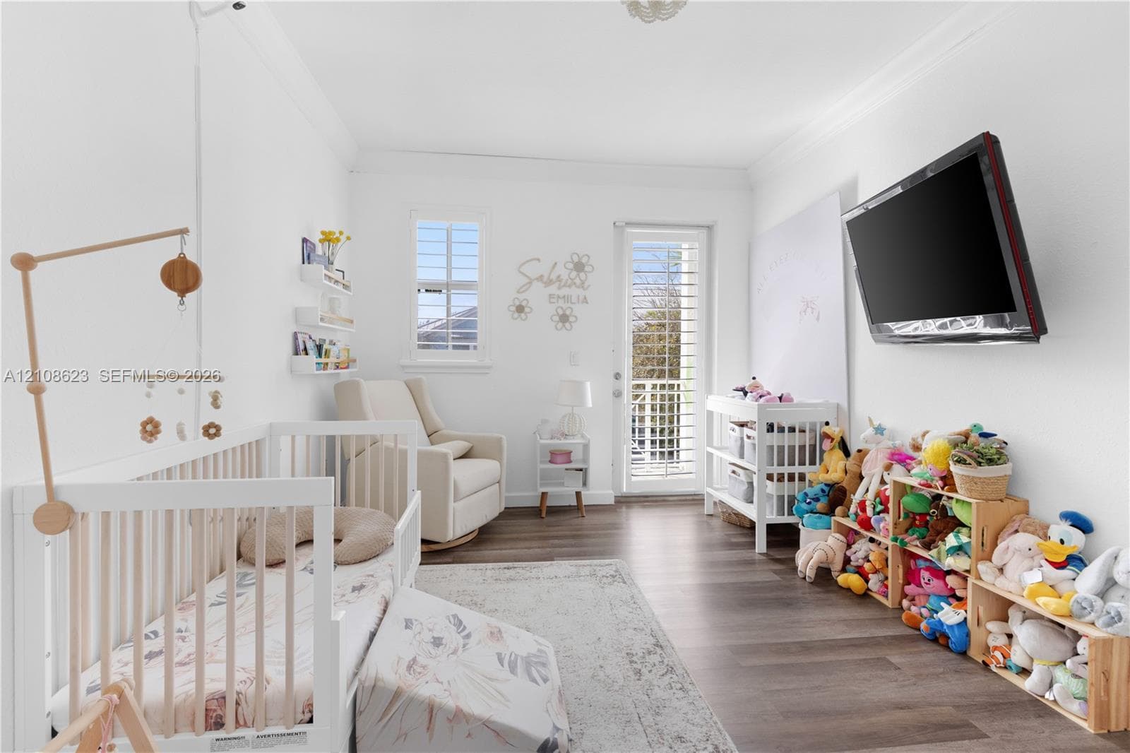 Neutral-toned room featuring wood-finish flooring, crown molding, a single-lite glass door, and a multi-pane window