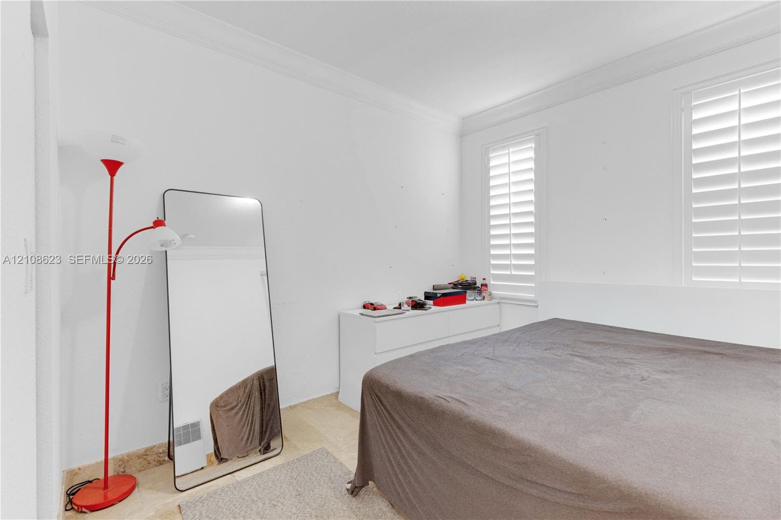 Room featuring neutral walls, crown molding, and dual windows outfitted with adjustable shutters